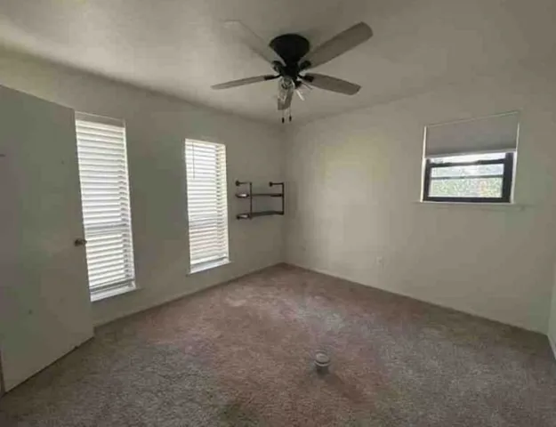 an empty room with windows and fan