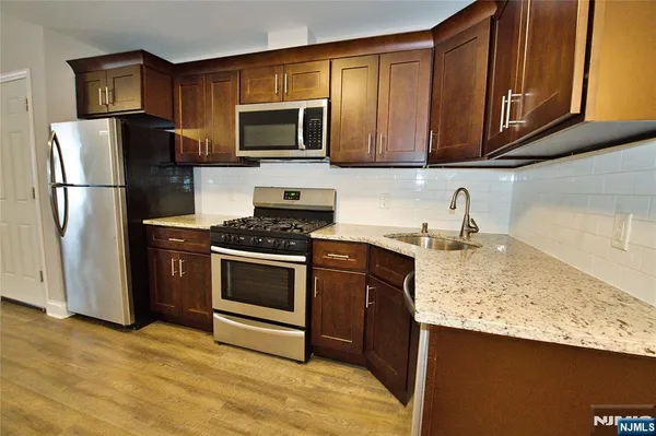 a kitchen with stainless steel appliances granite countertop a refrigerator stove top oven a sink and dishwasher