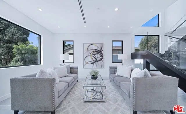 a living room with furniture a rug potted plant and a large window