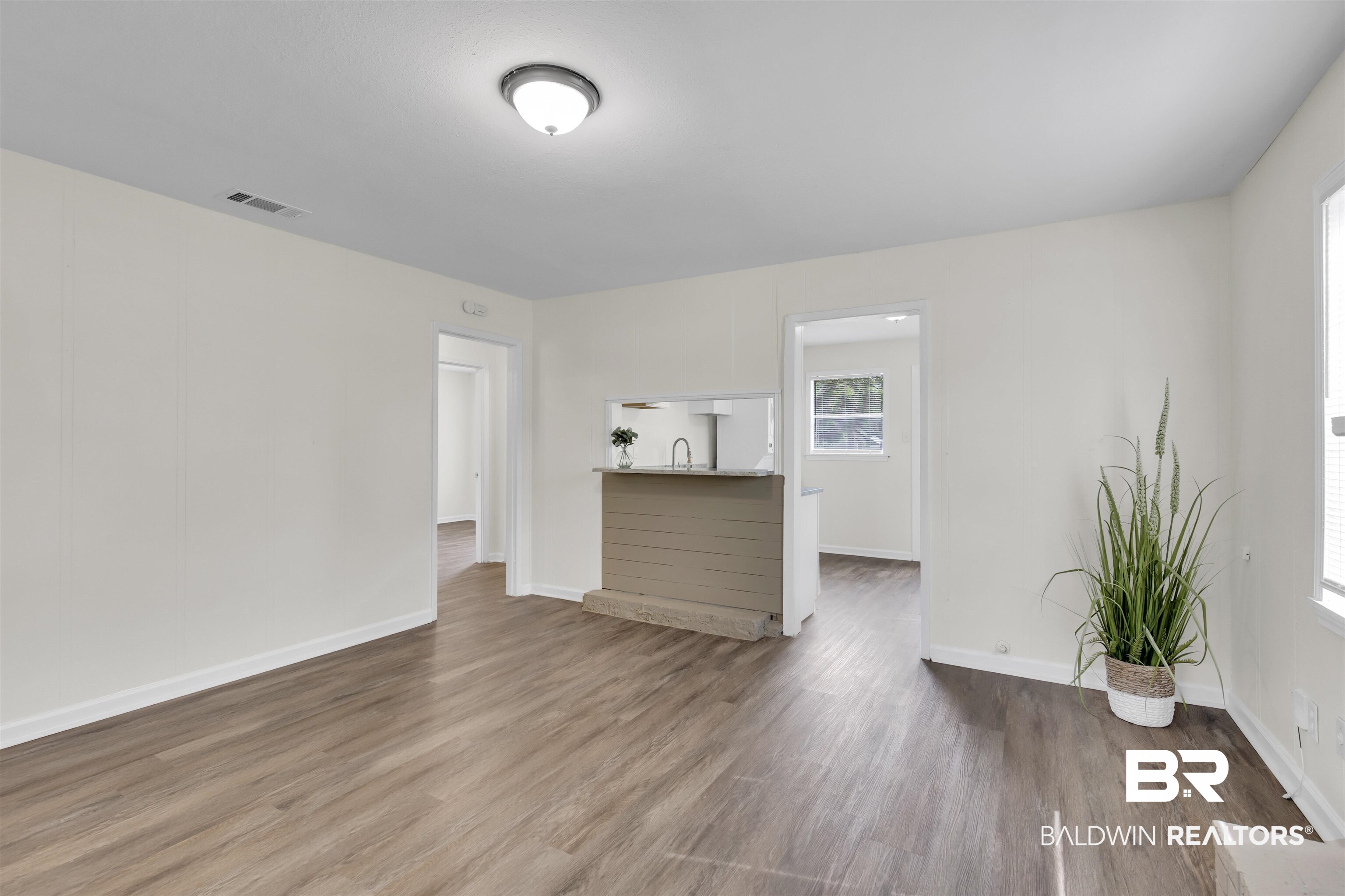 9241 Vallaris Street North Mobile, AL 36608 - Photo 11 of 17 Unfurnished living room featuring baseboards, wood finished floors, visible vents, and a sink