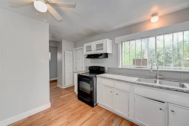 a kitchen with granite countertop a sink a counter space appliances and a window