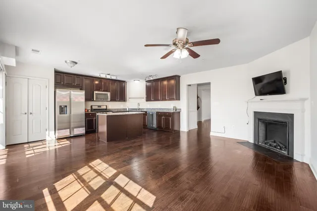 a view of a kitchen with furniture a ceiling fan and wooden floor