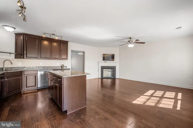 a living room with stainless steel appliances furniture a fireplace a flat screen tv and a kitchen view