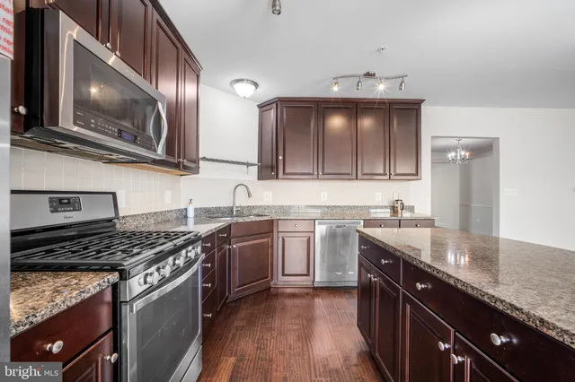 a kitchen with kitchen island granite countertop a stove top oven a sink a dining table and chairs with wooden floor