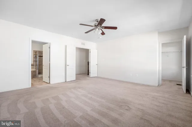 an empty room with closet and a ceiling fan