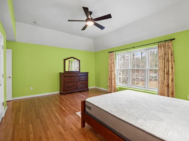 a spacious bedroom with a bed and wooden floor