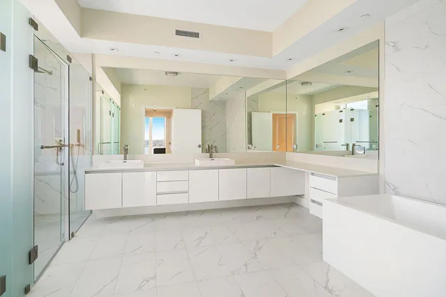 a large white bathroom with a double vanity sink mirror and a bathtub