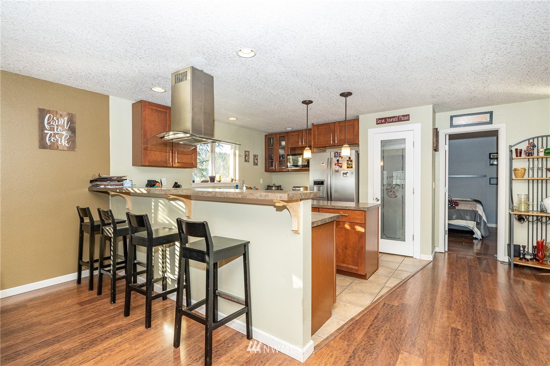 103 Mauerman Road Chehalis, WA 98532 - Photo 4 of 40 a kitchen with stainless steel appliances kitchen island granite countertop a refrigerator a stove a dining table and chairs with wooden floor