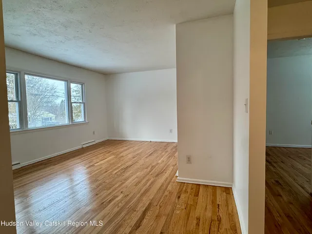 a view of an empty room with window and wooden floor