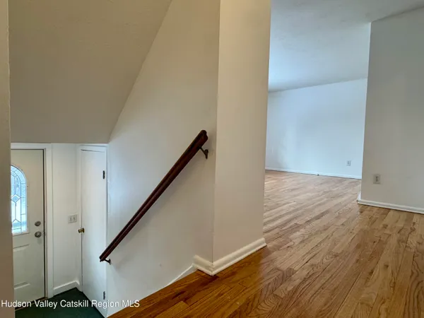 a view of a hallway with wooden floor and a bathroom