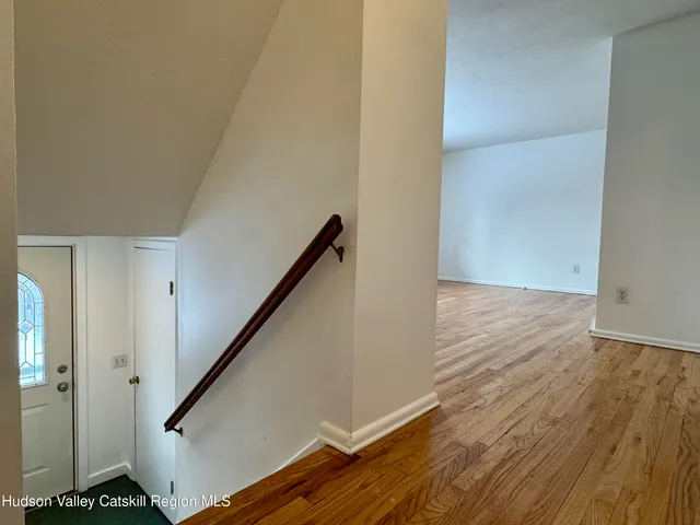 a view of a hallway with wooden floor and a bathroom