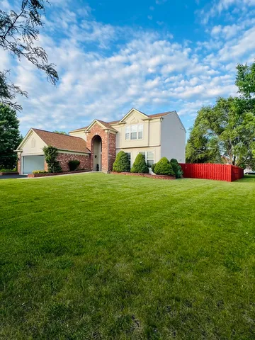 a view of a house with a big yard and large trees