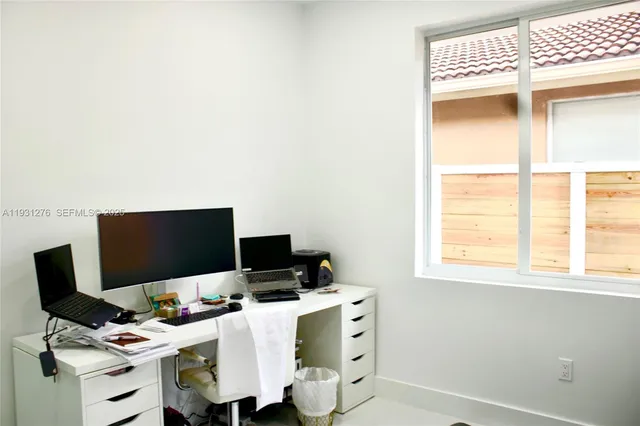 a view of a workspace with furniture and a window