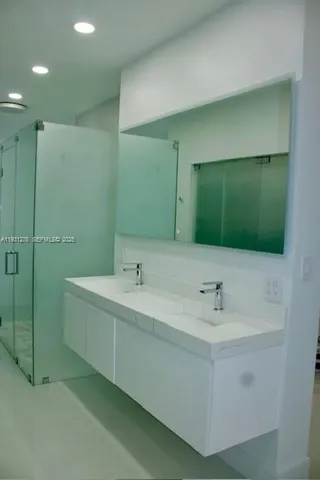 a bathroom with a double vanity sink mirror and bathtub