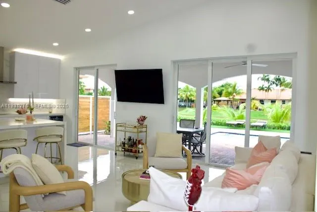 a living room with furniture a flat screen tv and floor to ceiling window