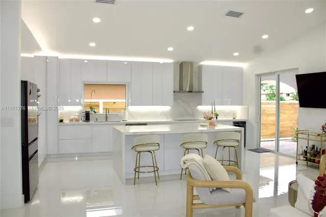 a kitchen with stainless steel appliances kitchen island granite countertop a table chairs sink and cabinets