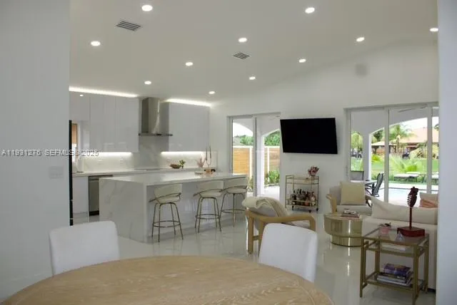 a living room with furniture a flat screen tv and kitchen view