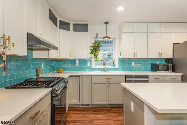 a kitchen with stainless steel appliances a stove a sink and white cabinets