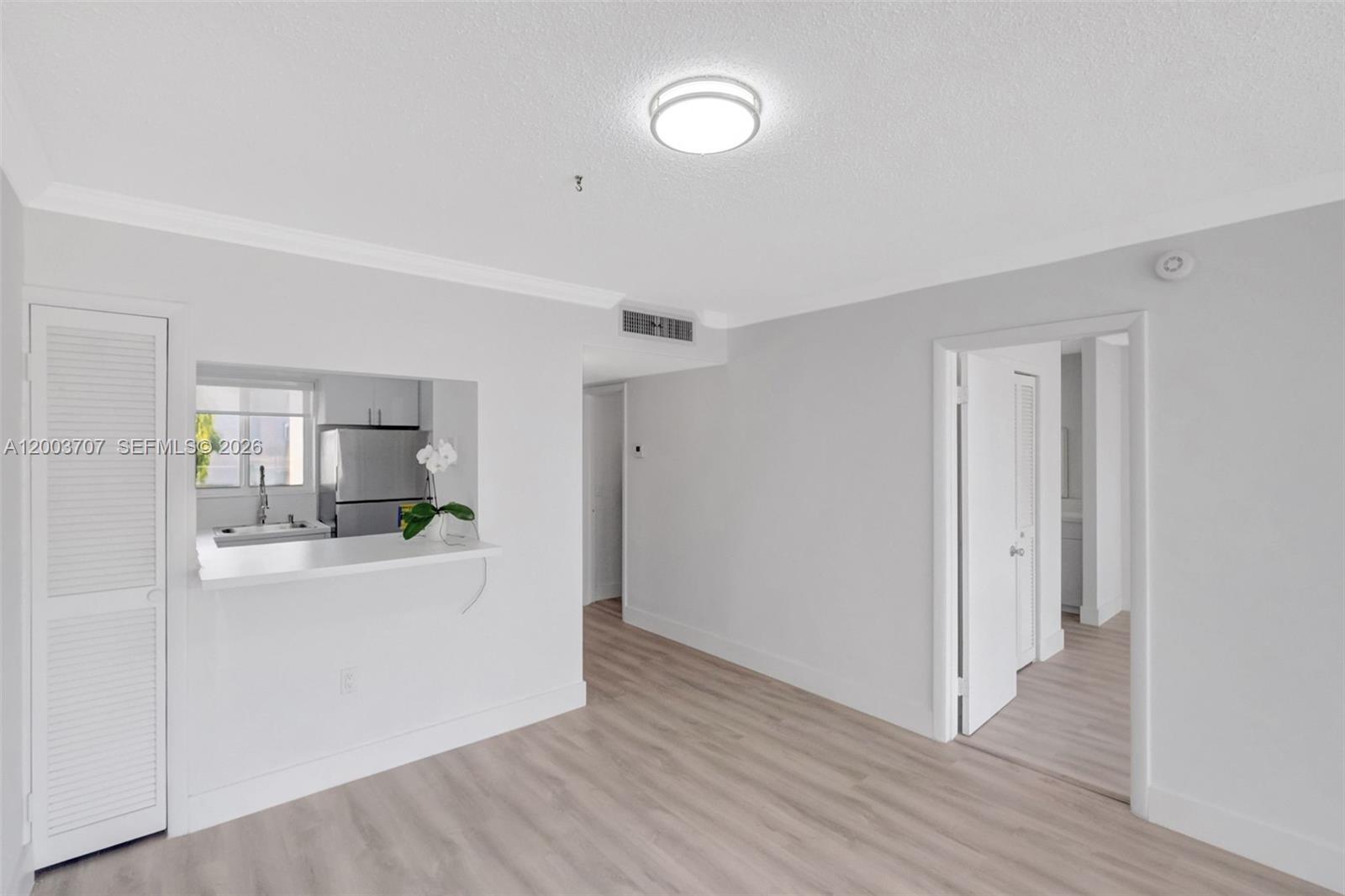 1345 Lincoln Road, Unit 501 Miami Beach, FL 33139 - Photo 16 of 33 a view of a kitchen and an empty room with wooden floor