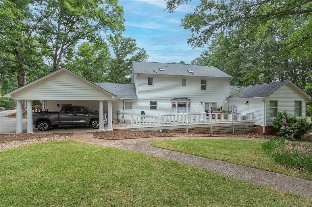 203 Oak Hollow Pendleton, SC 29670 - Photo 36 of 50 White siding and a dark roof define this home's rear exterior, featuring a spacious deck with an accessible ramp.