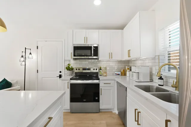 a kitchen with stainless steel appliances granite countertop a sink a stove a refrigerator a microwave and cabinets