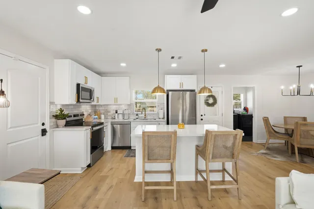 a kitchen with stainless steel appliances kitchen island granite countertop a table chairs microwave and sink