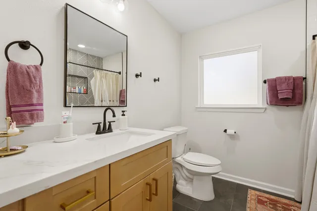 a bathroom with a toilet sink a mirror and vanity