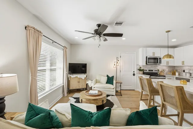 a living room with furniture a flat screen tv and kitchen view