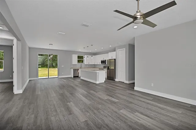 a view of a livingroom with wooden floor a ceiling fan and windows