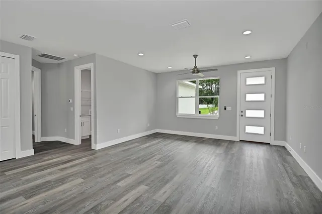 an empty room with wooden floor cabinet and windows