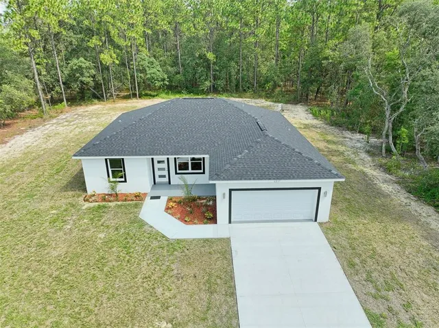 a aerial view of a house with yard and trees in the background