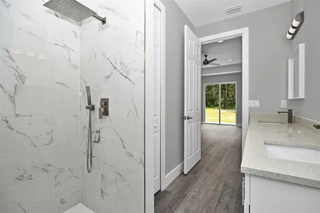 a bathroom with a granite countertop sink a mirror and shower