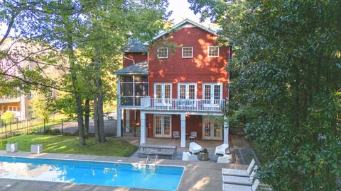 a view of a brick house with a big yard and large trees