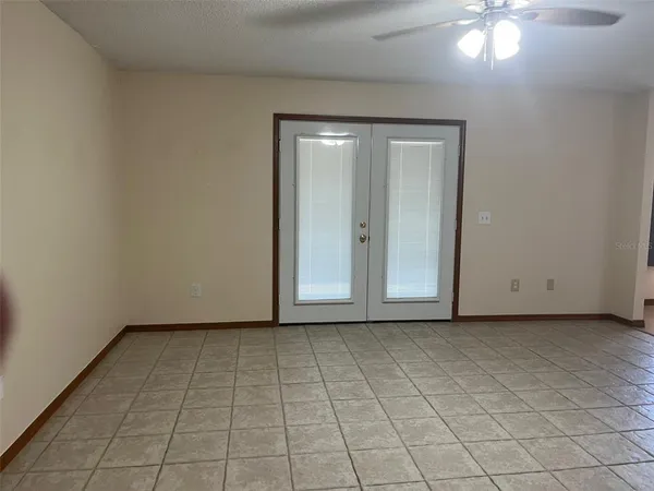 a view of an empty room and chandelier fan