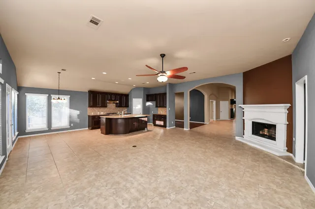 an empty room with a chandelier fan and a large window