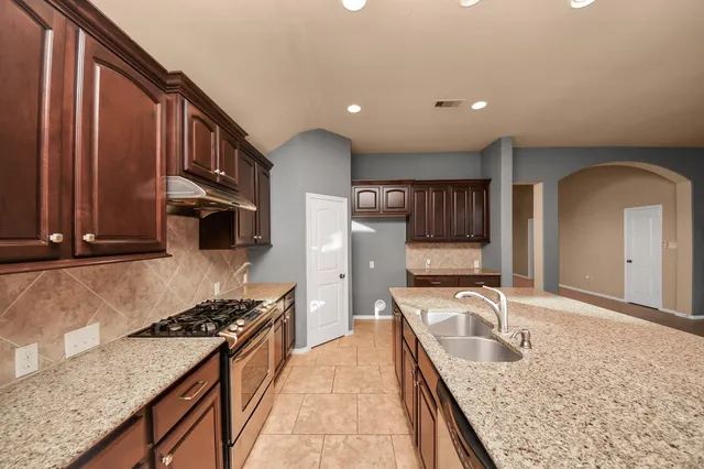 a kitchen with granite countertop a sink a counter top space and stainless steel appliances
