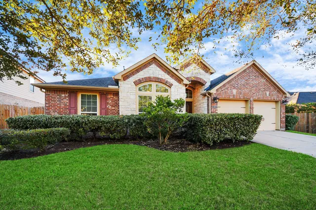 a view of a house with a small yard and a large tree
