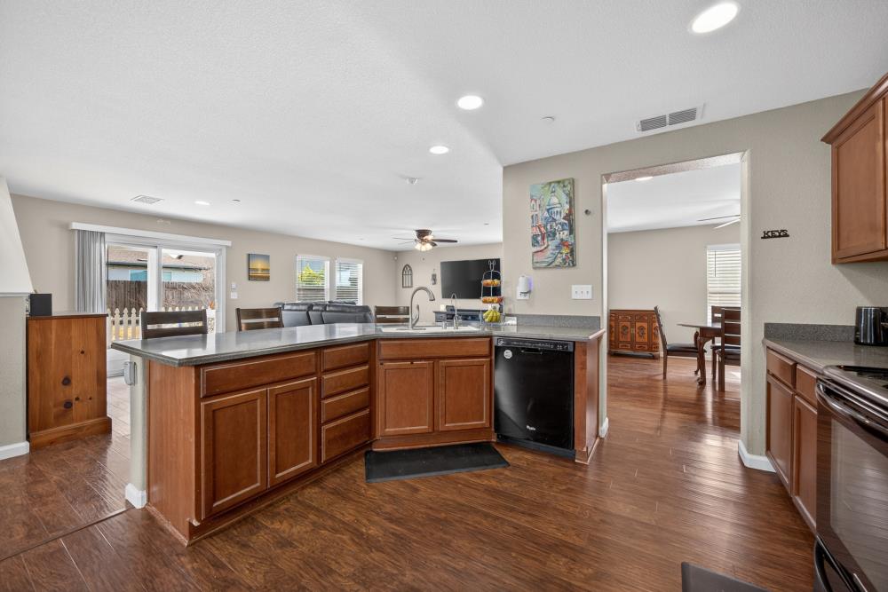 7467 Garden Ridge Way Sacramento, CA 95829 - Photo 13 of 54 a kitchen with stainless steel appliances granite countertop a stove top oven a sink dishwasher and a refrigerator with wooden floor