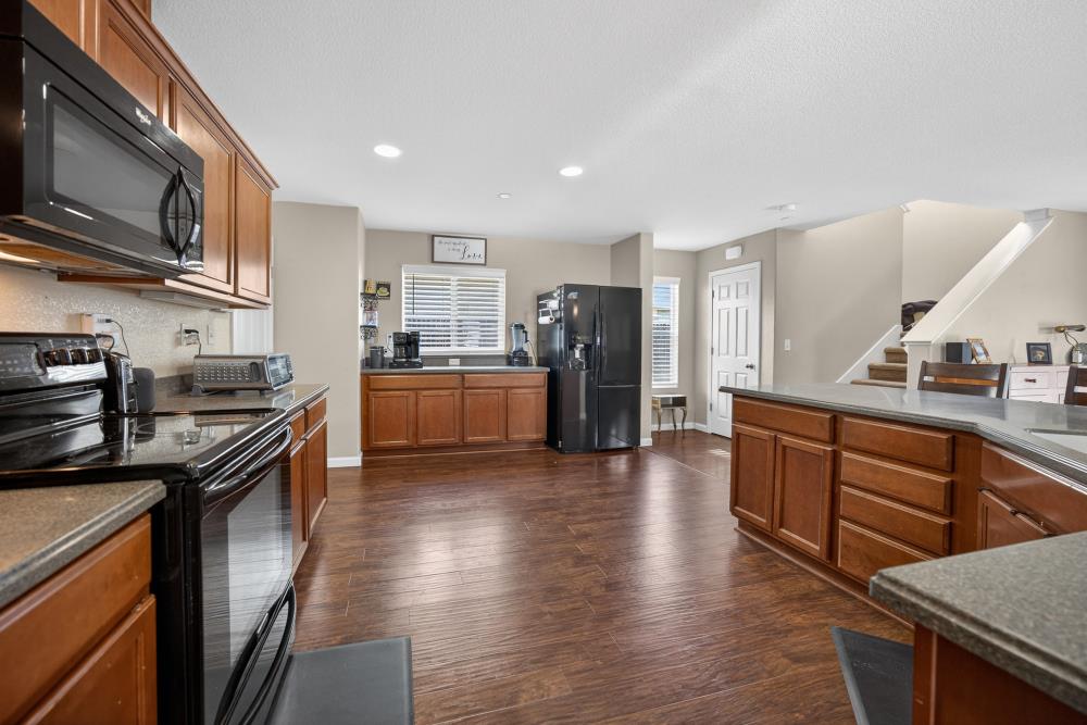 7467 Garden Ridge Way Sacramento, CA 95829 - Photo 14 of 54 a kitchen with stainless steel appliances granite countertop a stove top oven a sink dishwasher a refrigerator and cabinets with wooden floor