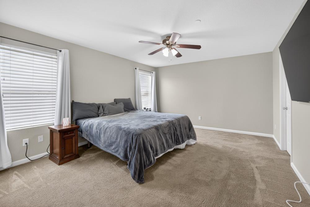 7467 Garden Ridge Way Sacramento, CA 95829 - Photo 23 of 54 a spacious bedroom with a bed and a chandelier