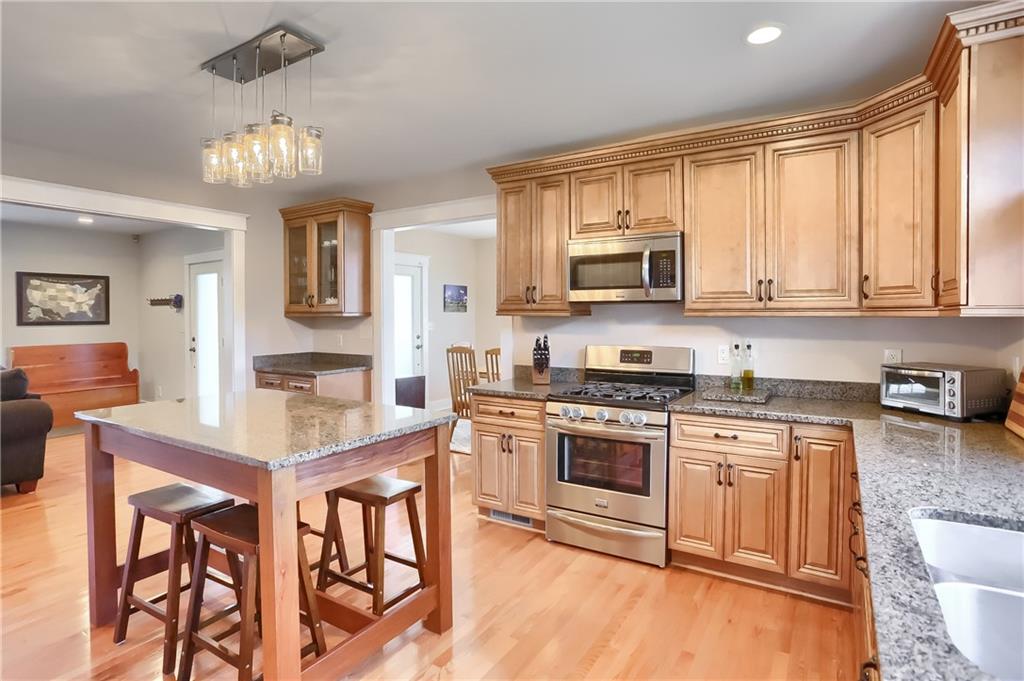 801 Main Street Coraopolis, PA 15108 - Photo 8 of 25 a kitchen with stainless steel appliances granite countertop a stove top oven a sink dishwasher a dining table and chairs with wooden floor