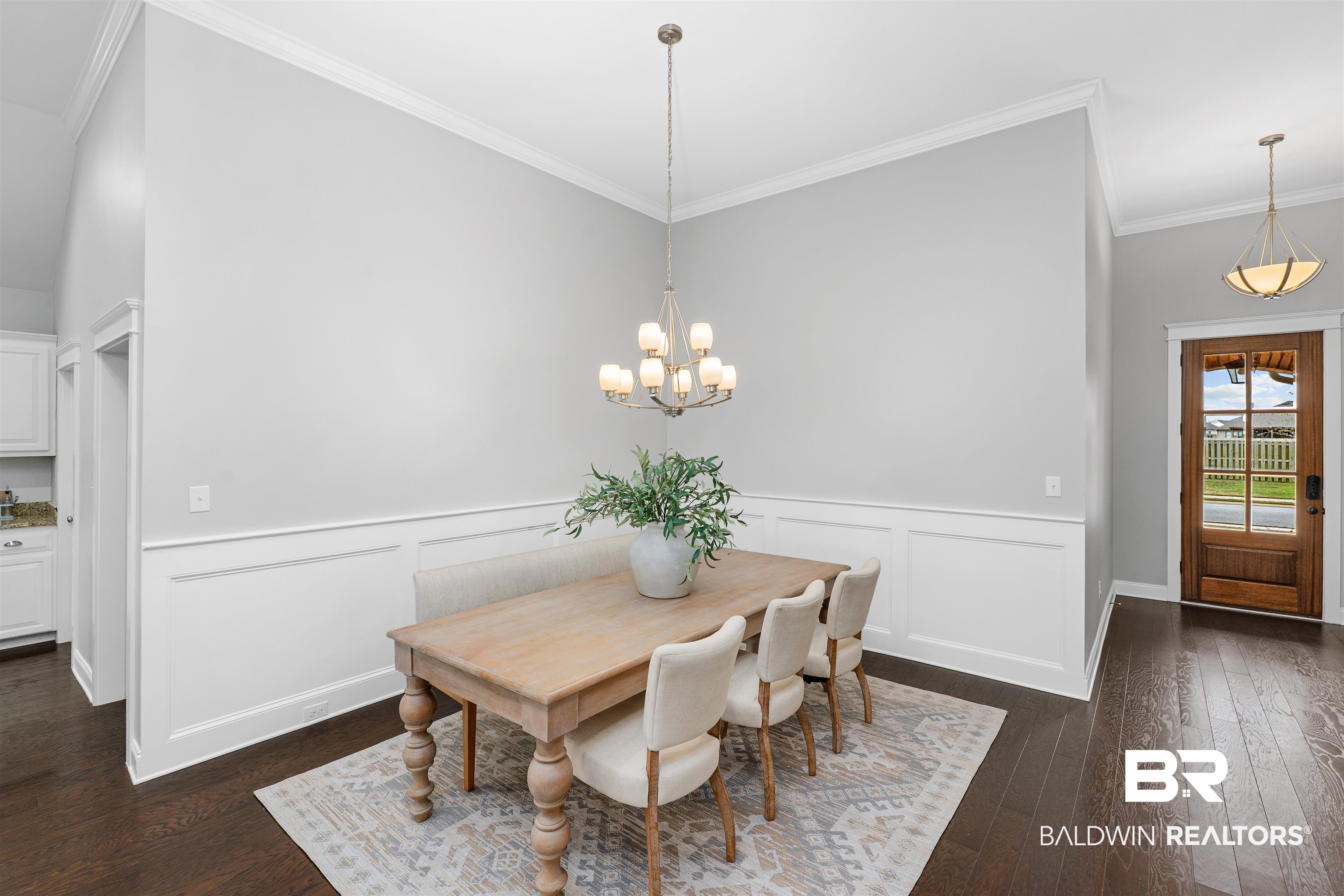 24838 Slater Mill Road Daphne, AL 36526 - Photo 4 of 46 Dining space with crown molding, dark wood finished floors, a chandelier, and a wainscoted wall