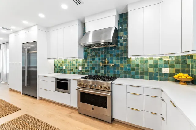 a large white kitchen with kitchen island a sink a stove a dining table and chairs