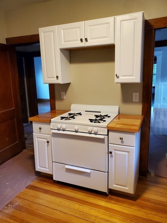 22 Allen Street, Unit 2 Arlington, MA 02474 - Photo 9 of 25 a kitchen with granite countertop a stove and a wooden floor