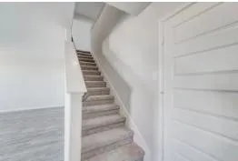 a view of staircase with white walls and white door