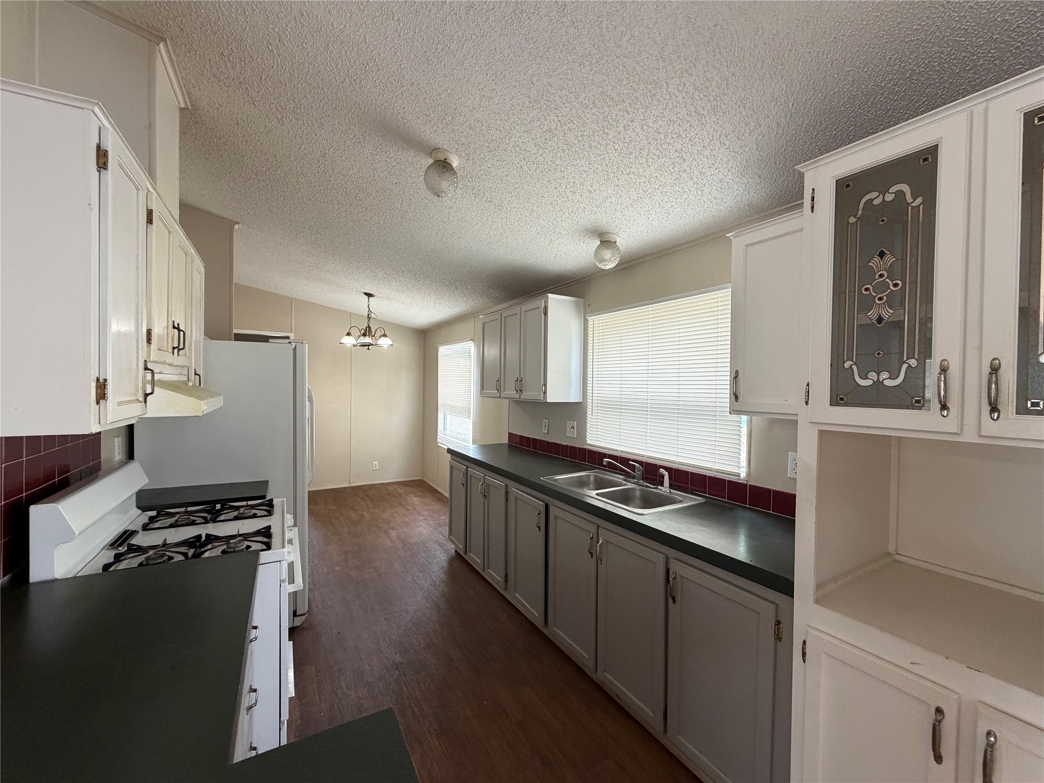 12609 Dessau Road, Unit 410 Austin, TX 78754 - Photo 4 of 11 Kitchen with white cabinetry, dark countertops, and a red tile backsplash