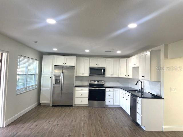 4800 Rilma Avenue, Unit 141 Sarasota, FL 34234 - Photo 4 of 19 a kitchen with stainless steel appliances granite countertop a refrigerator a sink dishwasher a stove and white cabinets with wooden floor