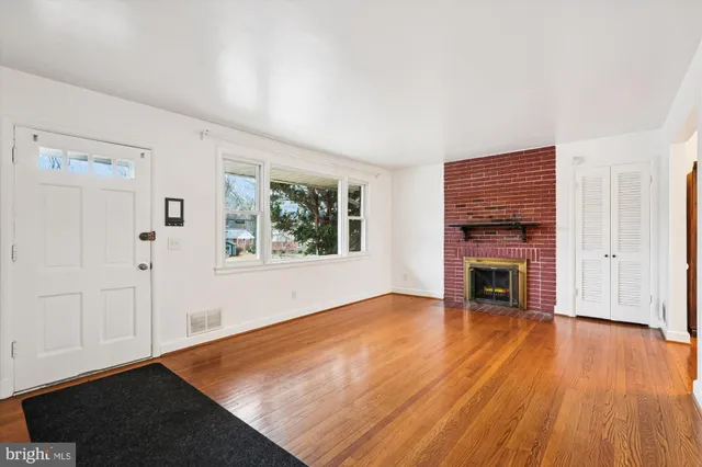 an empty room with wooden floor fireplace and windows