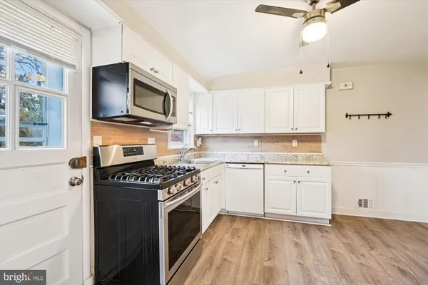 a kitchen with stainless steel appliances granite countertop a stove a sink and a microwave