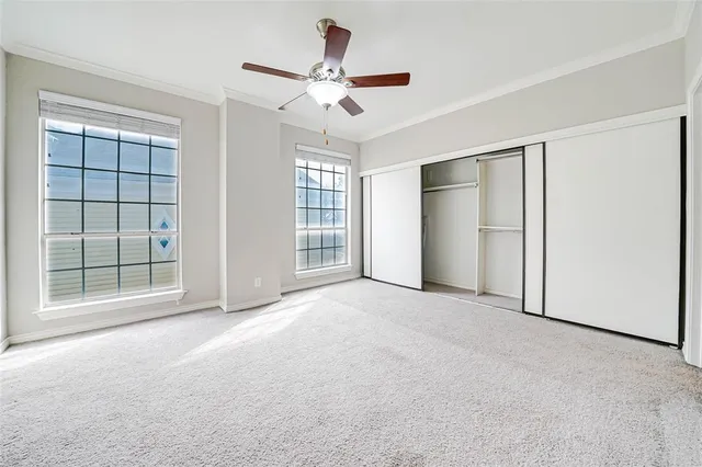 an empty room with windows and ceiling fan